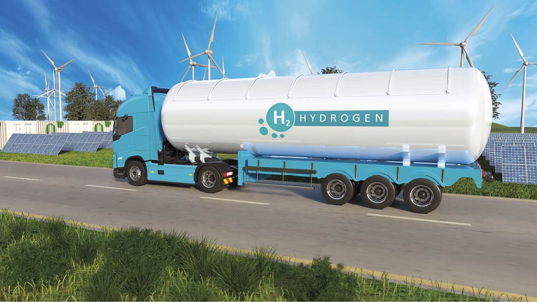 A hydrogen transport truck is moving along a road surrounded by green fields, wind turbines, and solar panels, showcasing renewable energy sources in action.